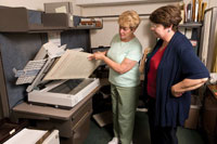 Patty Walker scans a document to make a digital copy as director of archives Rosanne Butler watches.