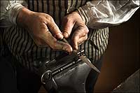 The blacksmith-strong hands of Ken Schwarz file a vice-held key forged in his shop.