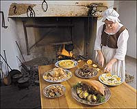 Barbara Ball slices lemons as garnish while working in the reconstructed kitchen of the Peyton Randolph House.
