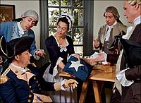 Betsy Ross shows General Washington the flag she created for the nation in her Philadelphia shop, or so we were told in school. But the facts are few and flimsy to support that account. From left, Ron Carnegie as Washington, Sam Miller, Brook Welborn as Ross, Mark Sowell, and Gerry Underdown as Col. George Ross.