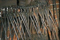 A collection of iron tongs used by the blacksmith to hold pieces of differing sizes and shapes.
