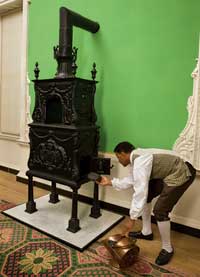 At the Governor’s Palace, interpreter Brandon Hewitt feeds coal into an example of a  Abraham Buzaglo heating stove.