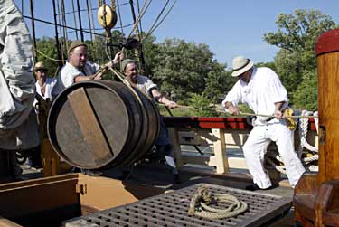 Jamestown Settlement interpreters Michael Lund, Homer Lanier, Steve Martin, and Joseph Freitus, costumed as seventeenth-century sailors, lower a cask of Virginia wine in the hold of the replica Susan Constant as if for shipment to England. - Dave Doody