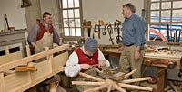 Author Jay Gaynor with wheelwrights Paul Zelesnikar, left, and Andrew DeLisle, working on a spoke, at the Elkanah Deane Shop