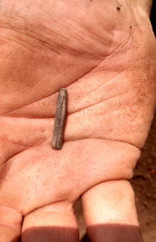 Hand holding a slate pencil fragment.