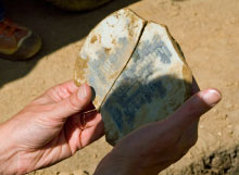 An archaeologist holds fragments of a basin.