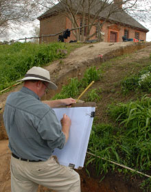 An archaeologist writes on a large clipboard.