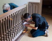 Historians take paint samples from a baluster.